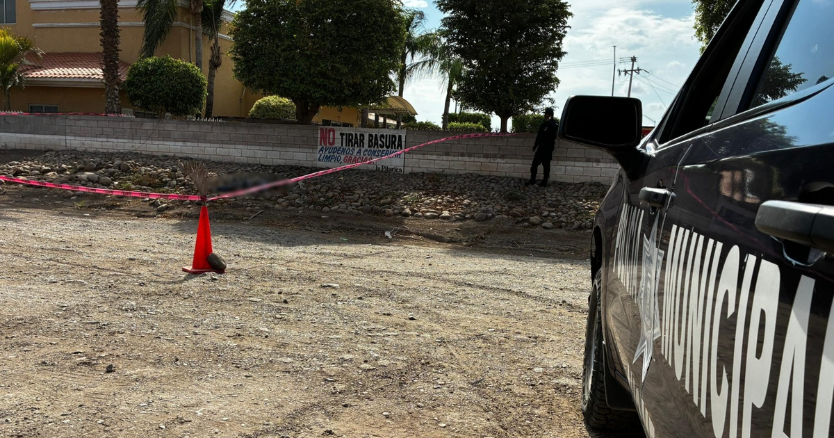 Auto de policía y cinta de advertencia en escena de investigación en Los Mochis