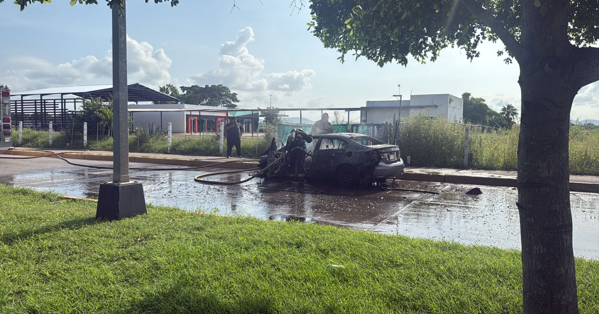 Automóvil incendiado en Mazatlán con bomberos y camión de bomberos presentes