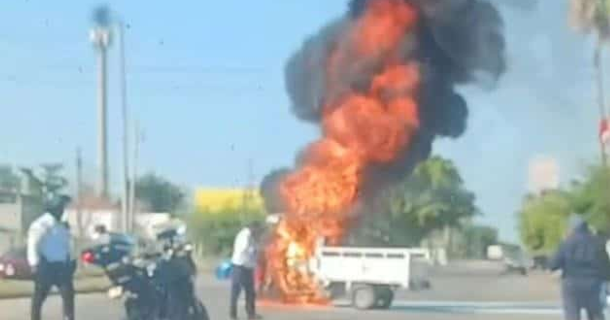 Motocarro en llamas en gasolinera de Los Mochis, con humo negro y llamas naranjas, rodeado de personas y una motocicleta.