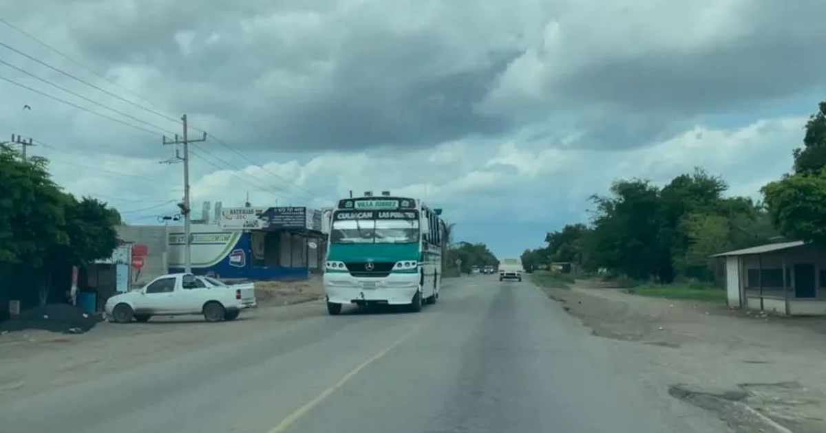 Autobús en carretera de Sinaloa con cielo nublado y comercios al fondo