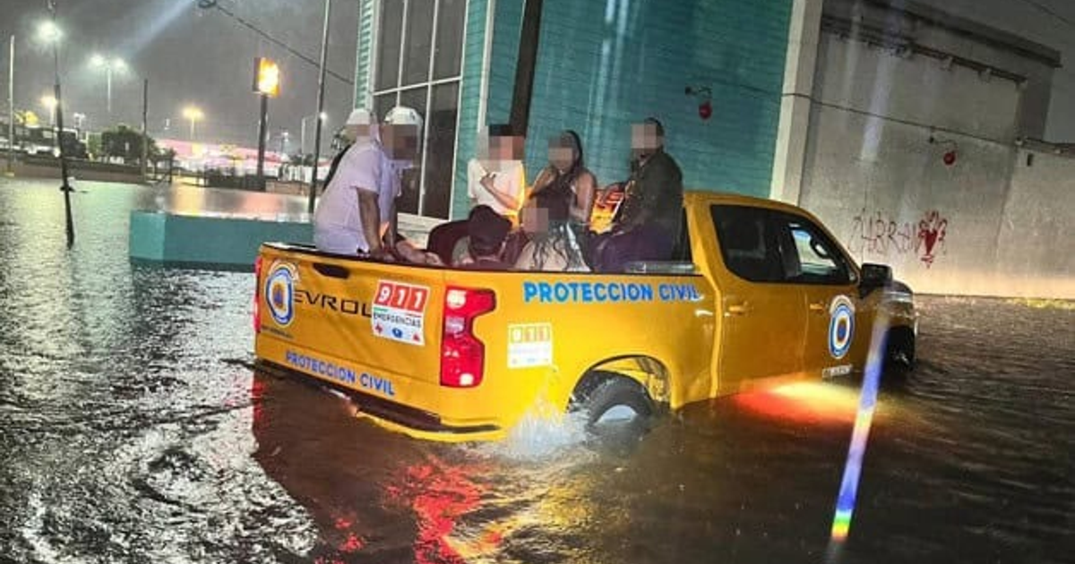 Camioneta de Protección Civil en calle inundada de Mazatlán con personas en la parte trasera.