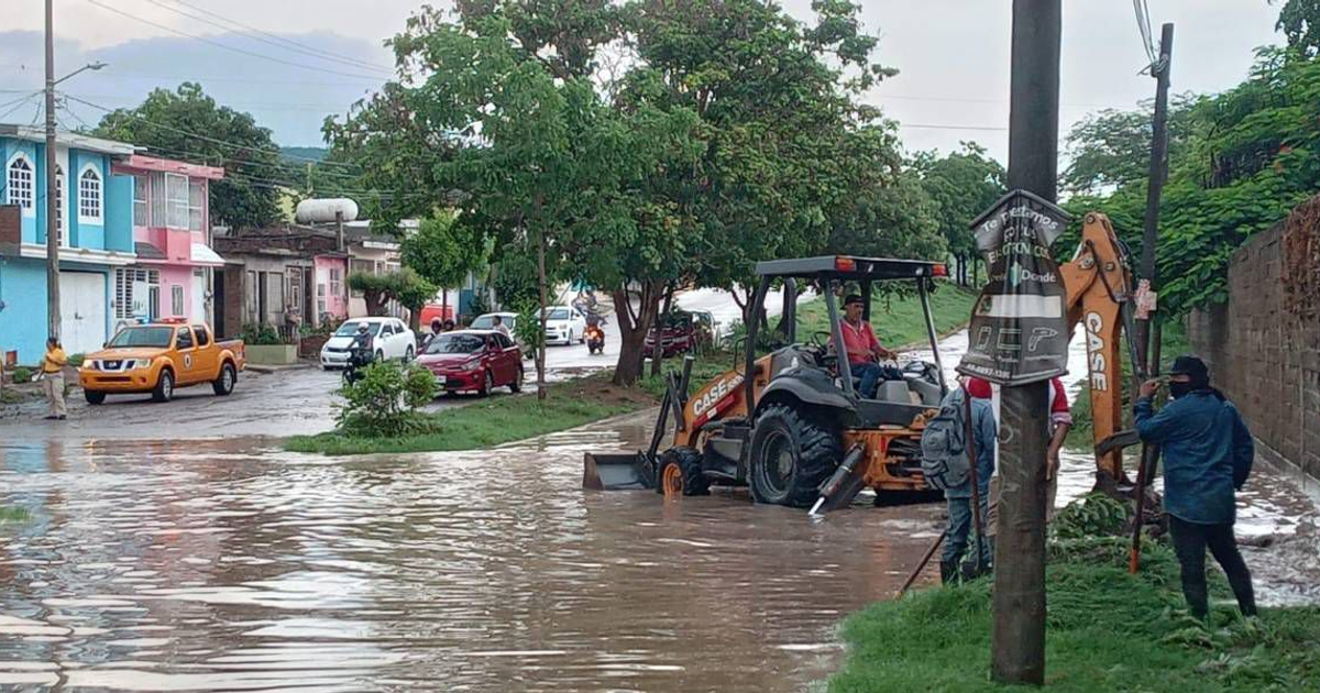 Calle inundada en avenida Genaro Estrada con maquinaria trabajando para desfogar agua.