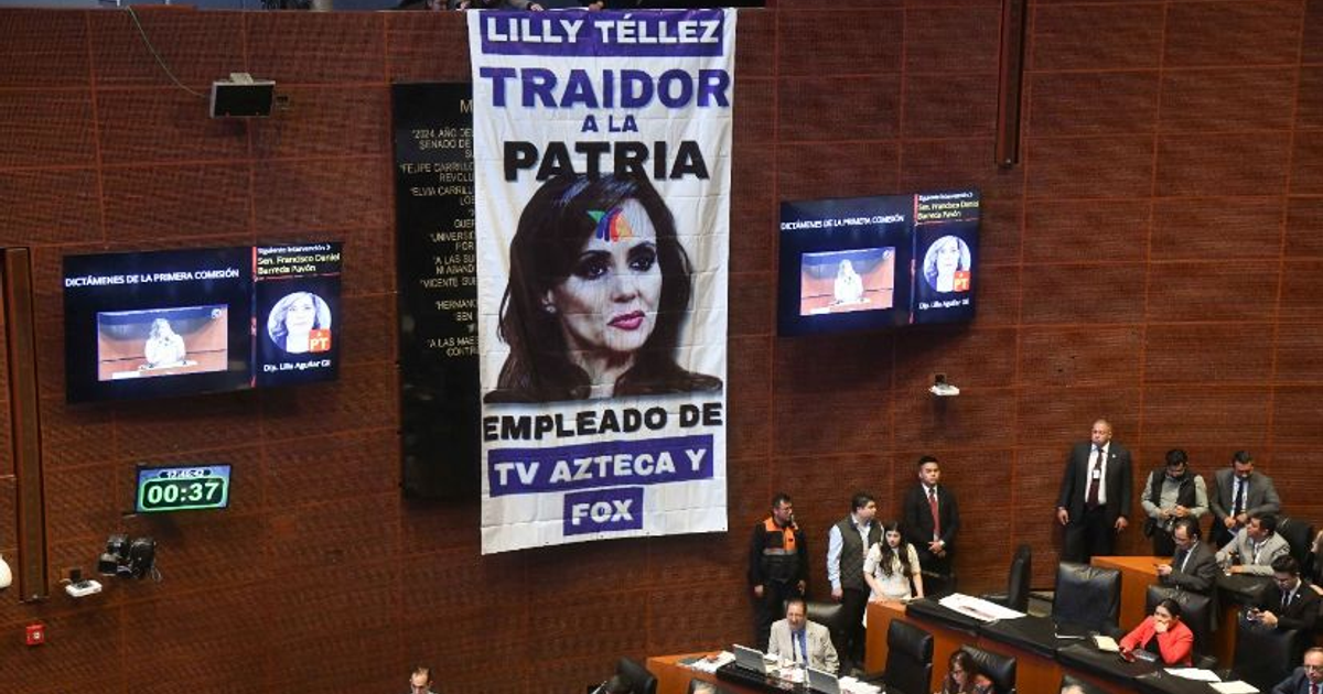 Sesión legislativa en México con cartel de 'traidor a la patria' y pantallas mostrando presentaciones.