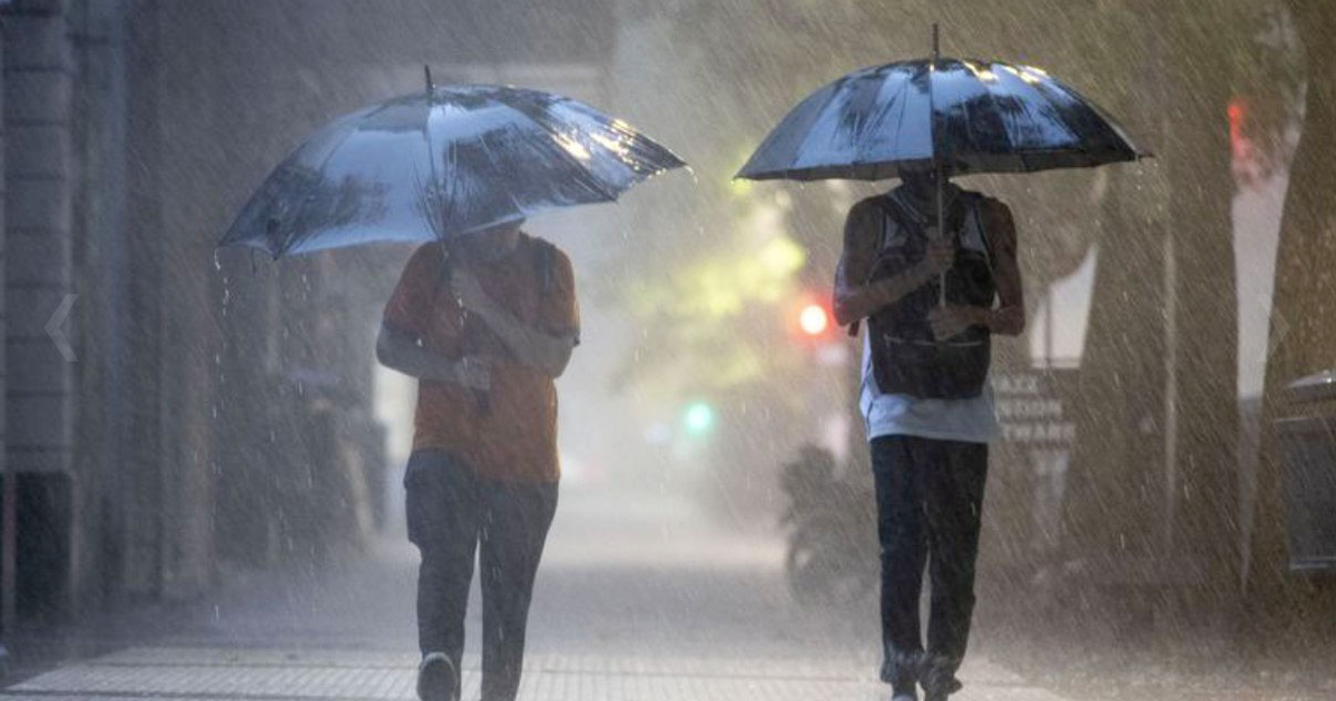Dos personas con paraguas caminando bajo la lluvia en un día tormentoso en Sinaloa.