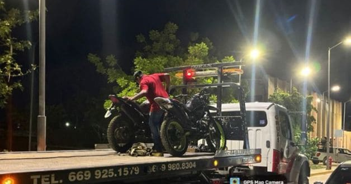 Hombre manipulando motocicletas en plataforma de remolque durante operativo nocturno en Mazatlán