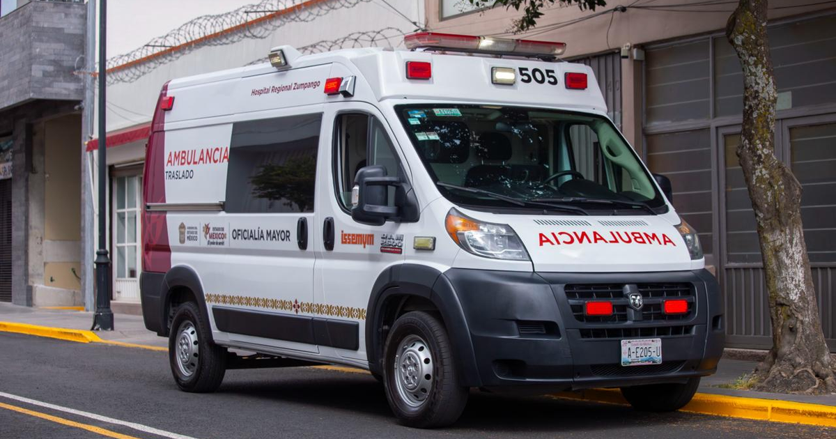 Ambulancia estacionada con luces de emergencia en un entorno urbano, vinculada a un incidente en carretera.