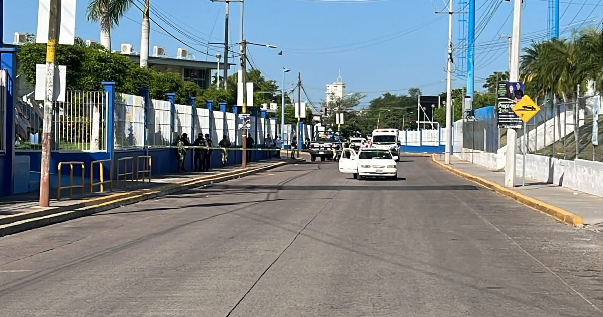 Calle en Culiacán con vehículos y personas tras ataque armado en Preparatoria Emiliano Zapata.