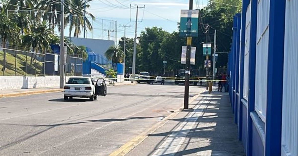 Coche blanco estacionado en escena del crimen en Culiacán, con cinta amarilla y personas alrededor.