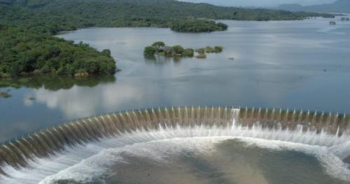 Embalse y represa en Sinaloa con vertedero activo, rodeado de vegetación y montañas.