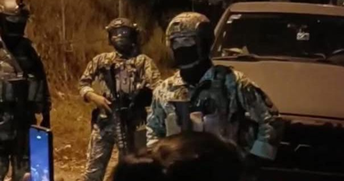 Militares armados en operativo nocturno en Guamúchil, rodeando una vivienda con un vehículo presente y una persona grabando con un móvil.