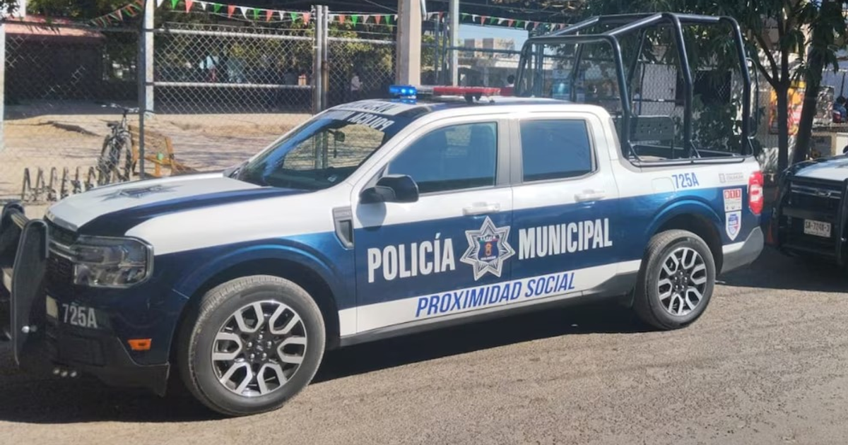 Vehículo de policía municipal azul y blanco con estructura trasera en área cercada.