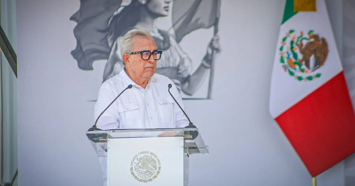 Gobernador Rubén Rocha Moya en evento de seguridad en Sinaloa, con bandera de México al fondo.