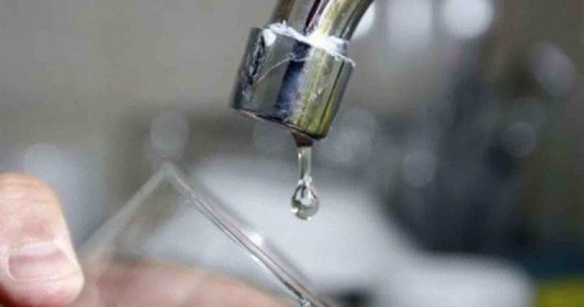 Grifo goteando agua en cocina con vaso para recogerla