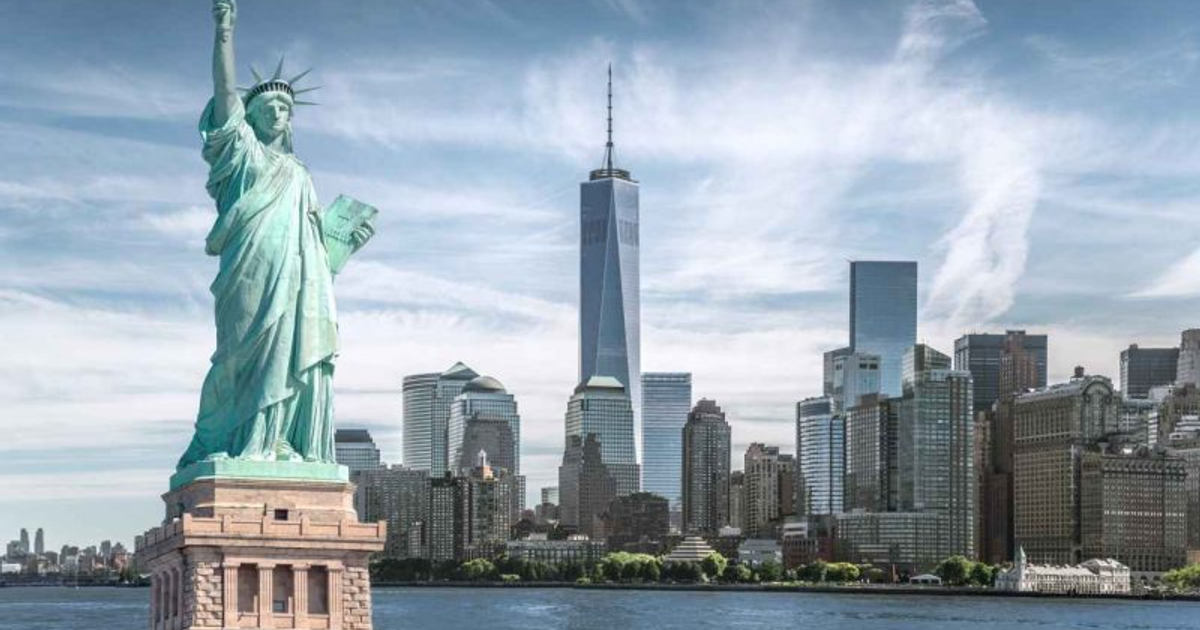 Estatua de la Libertad frente a rascacielos de Nueva York, cielo nublado