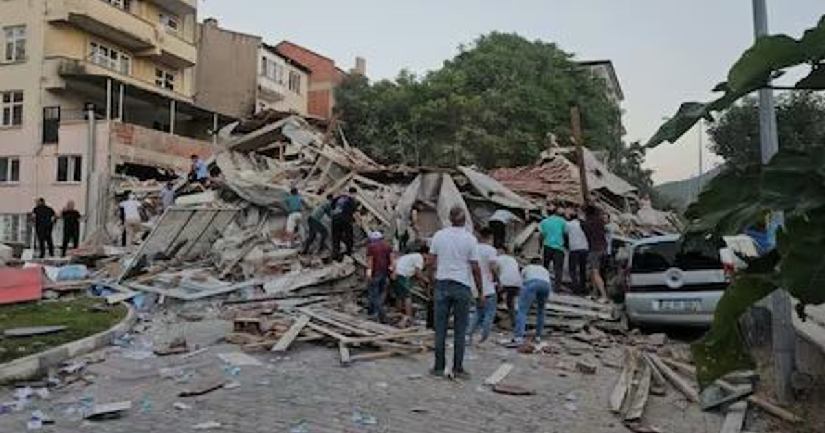 Edificio colapsado en Sındırgı, Turquía, tras terremoto de magnitud 6.1, con escombros y personas en la escena.