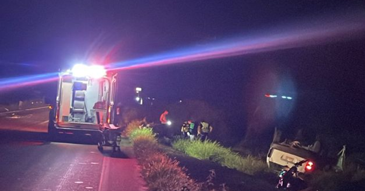 Ambulancia iluminando un vehículo volcado en la carretera México 15 durante la noche.