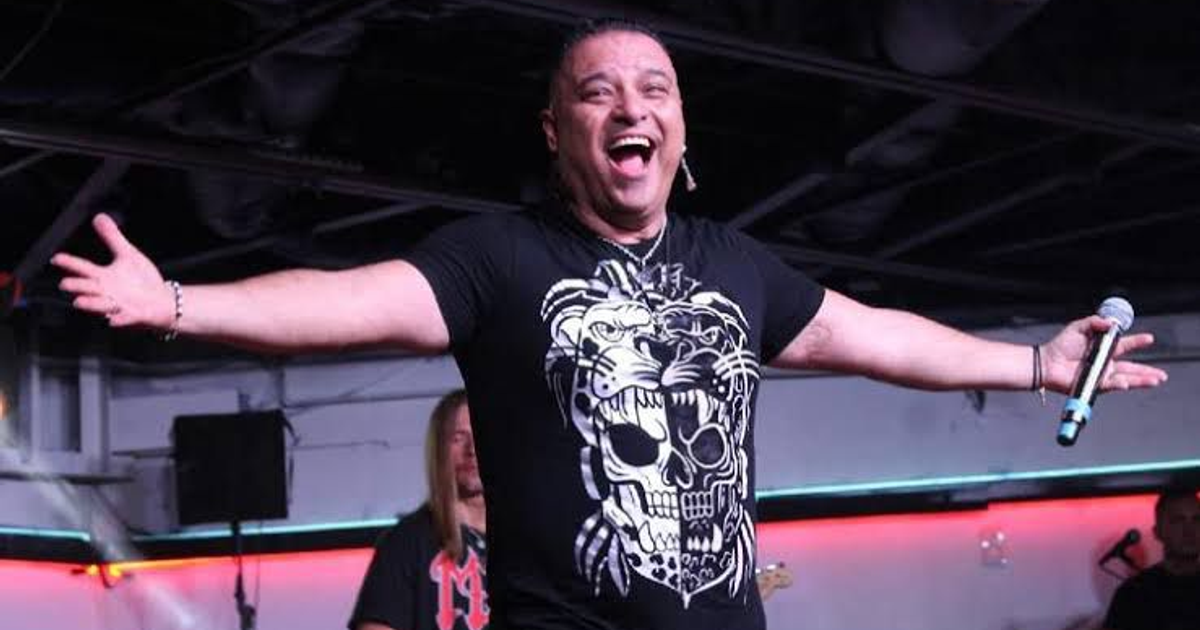 Xava Drago actuando en el escenario con una camiseta negra y luces de colores de fondo.