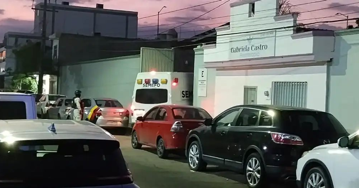 Calle en Culiacán con ambulancia y vehículos estacionados al atardecer
