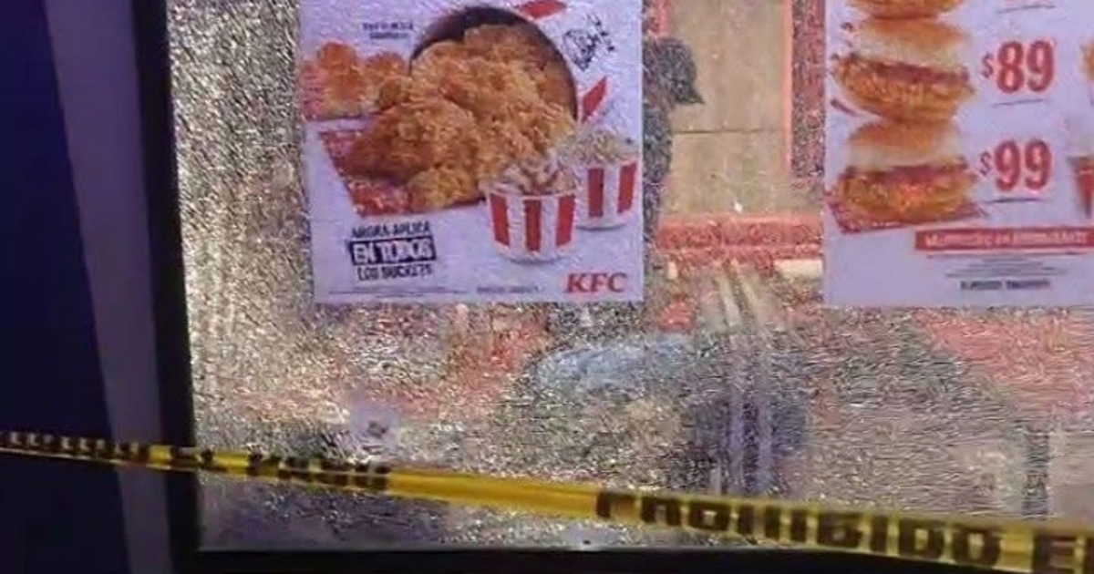 Ventana rota en KFC de Córdoba con cinta de advertencia amarilla