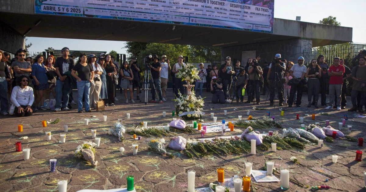 Personas reunidas en un altar conmemorativo con una cruz y velas, en memoria de las víctimas del festival Axe Ceremonia.