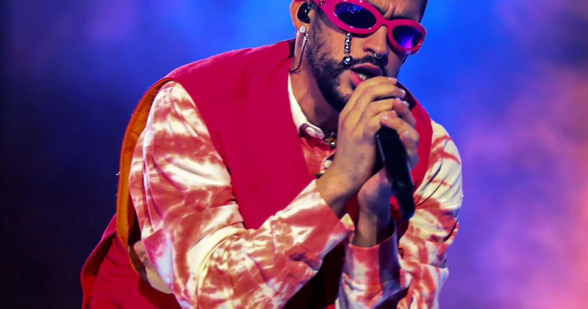 Bad Bunny en el escenario con gafas de sol rosas y ropa colorida durante un concierto en Puerto Rico.