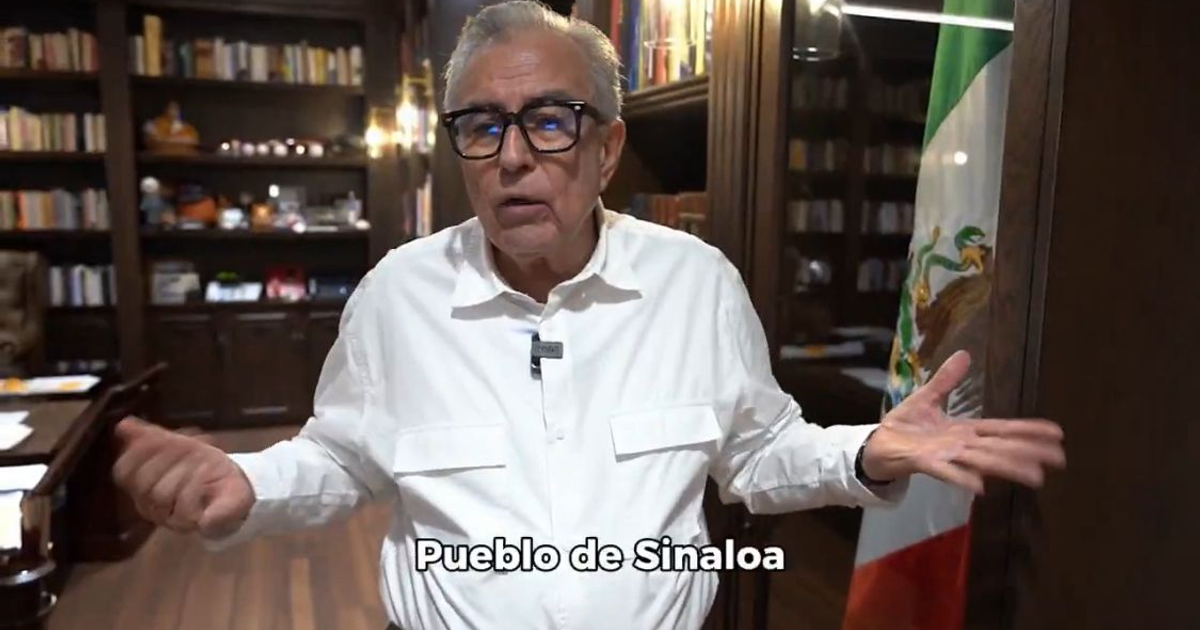 Hombre con camisa blanca y gafas en oficina con bandera de México y texto 'Pueblo de Sinaloa'.