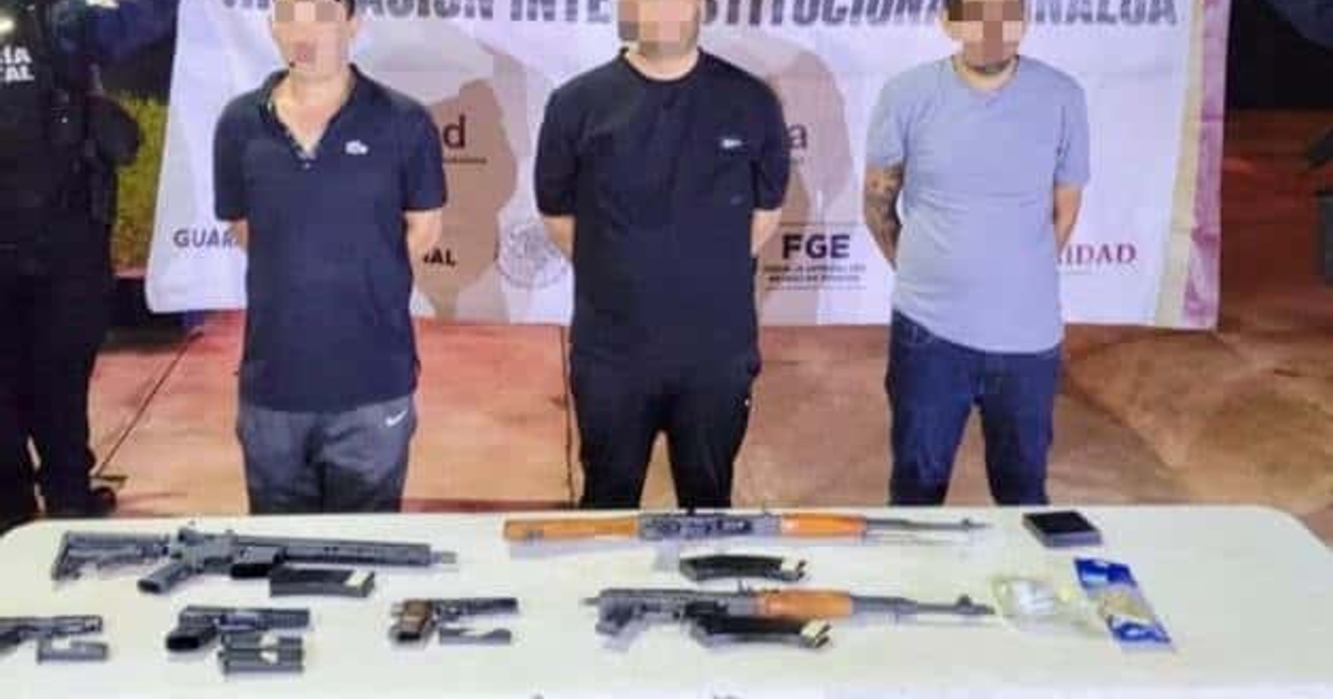 Tres personas detenidas frente a una mesa con armas incautadas durante un operativo policial en Culiacán.