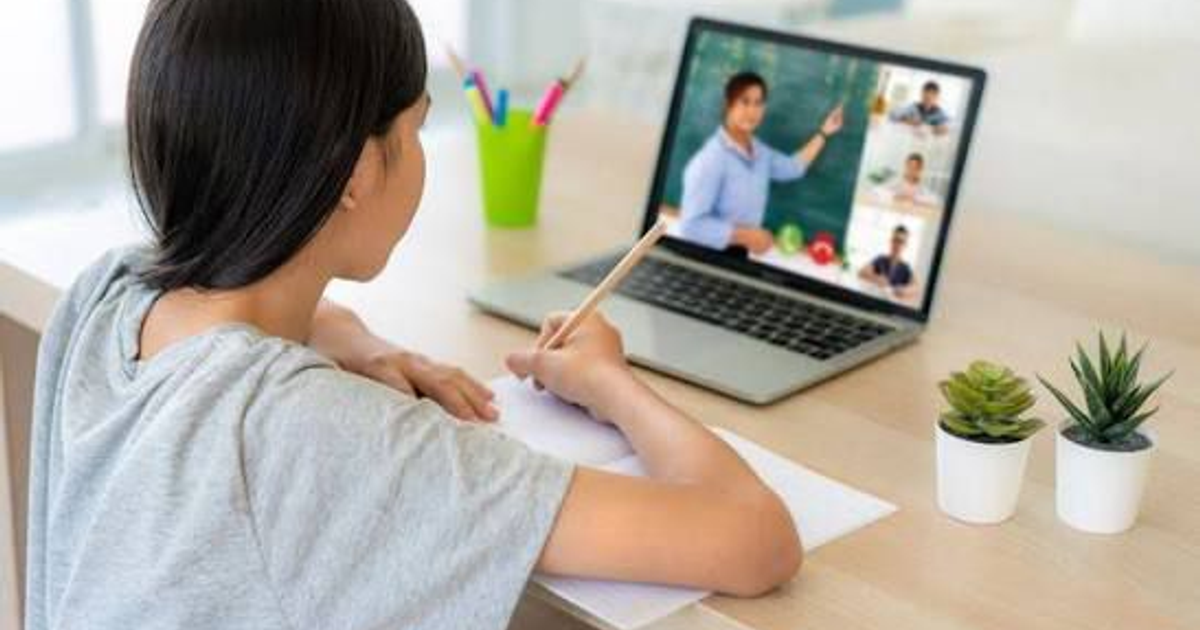 Estudiante tomando notas durante una clase virtual en casa