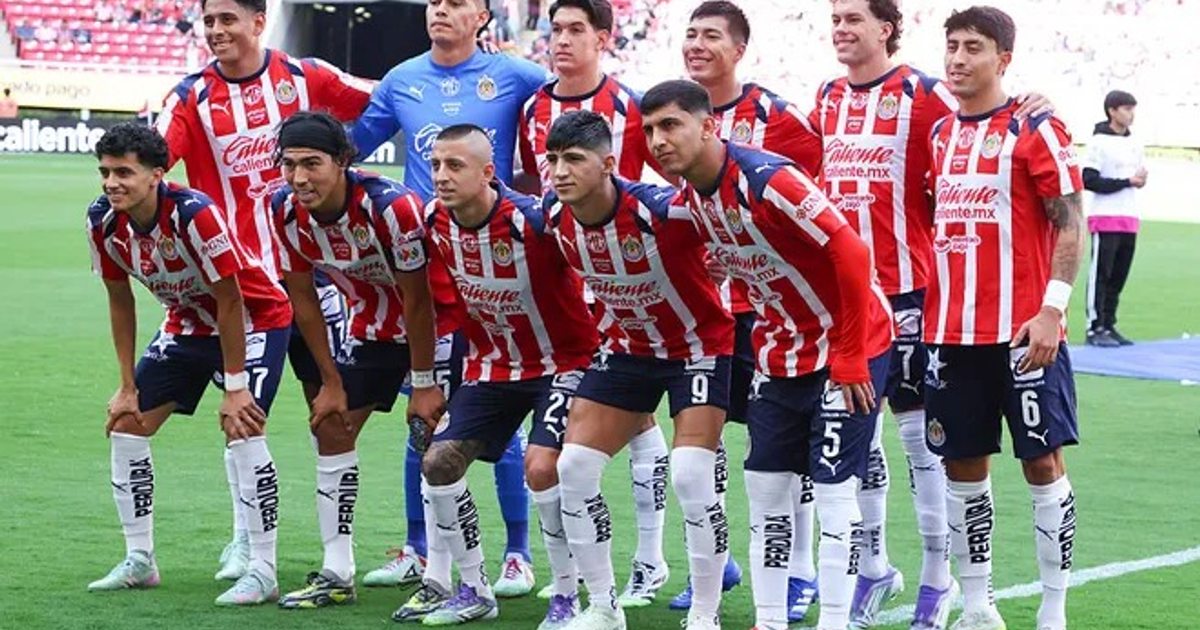 Equipo de fútbol posando en el campo antes del Clásico Nacional, con jugadores en camisetas rojas y blancas y un portero en azul.