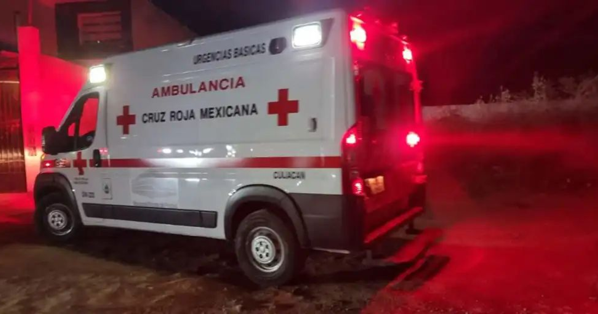 Ambulancia de la Cruz Roja Mexicana iluminada en la noche, estacionada cerca de un edificio con luces rojas.