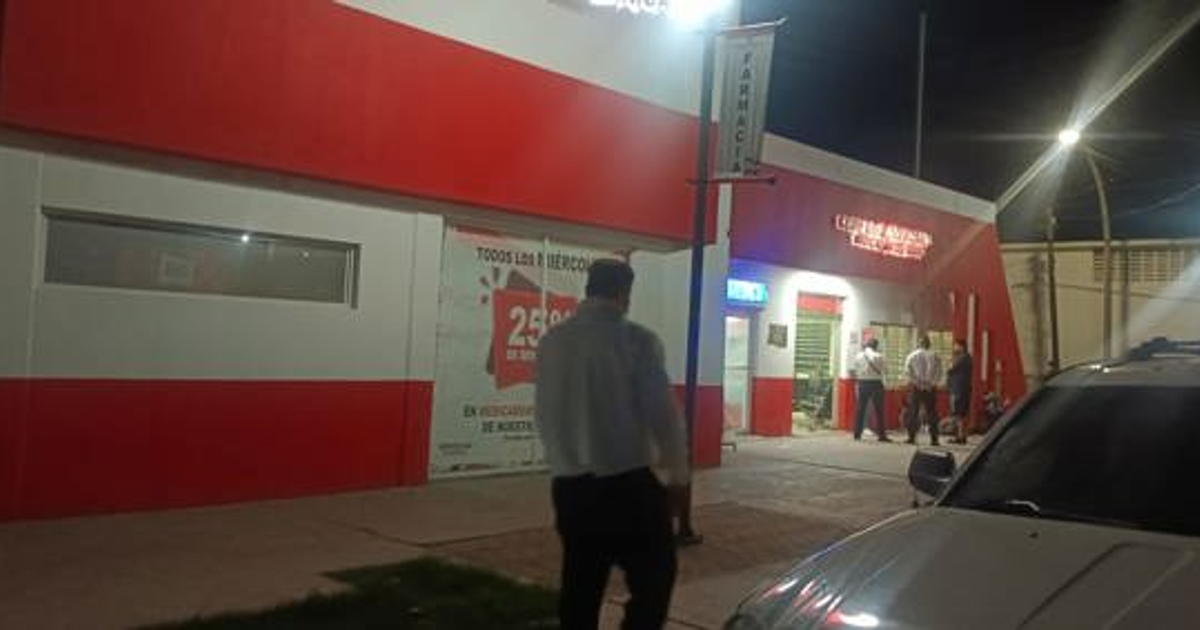 Fachada de tienda iluminada con cartel de promoción del 25% y personas en la entrada, de noche.