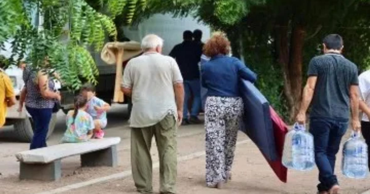 Personas desplazadas en Culiacán cargando pertenencias al aire libre