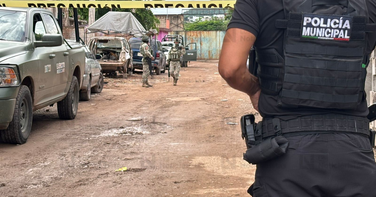 Policía y soldados en escena de crimen en Culiacán, con vehículos dañados y área acordonada.