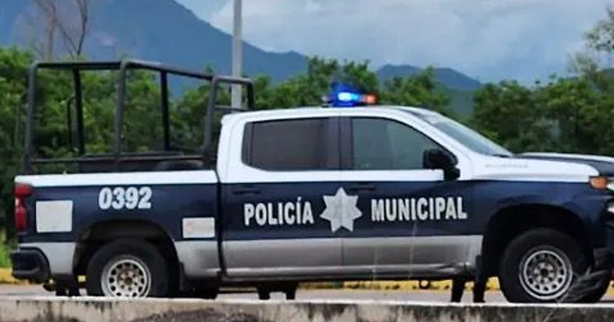 Camioneta de Policía Municipal azul y blanca con luces, en un paisaje de árboles y montañas.