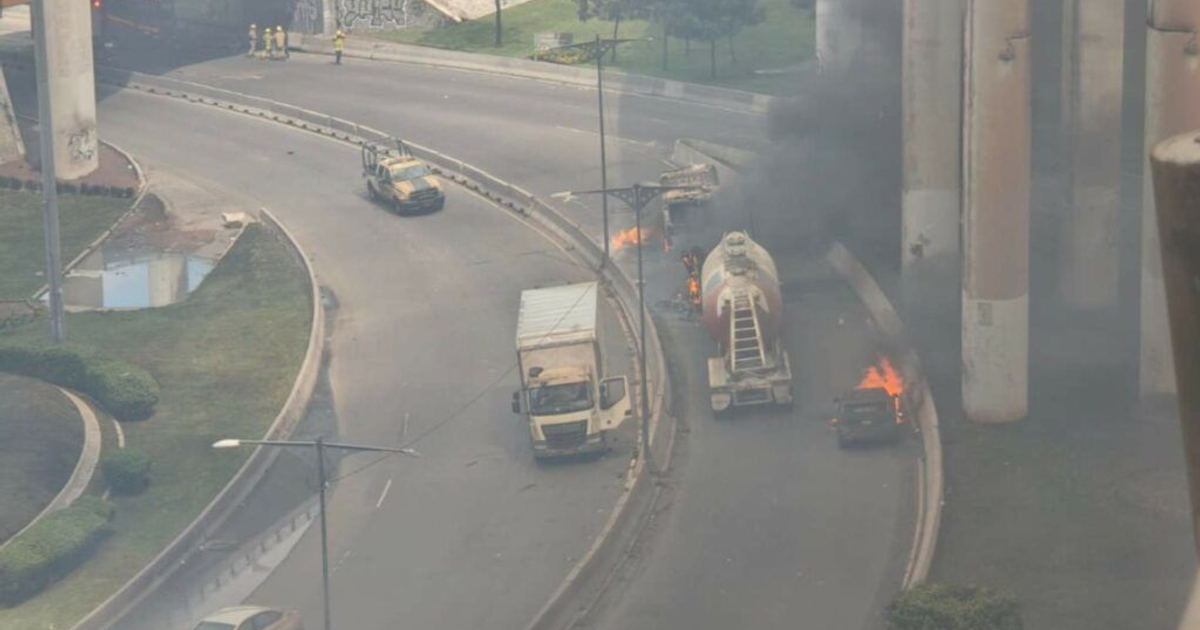 Escena de emergencia en Iztapalapa tras explosión de pipa de gas LP, con vehículos en llamas y bomberos presentes.