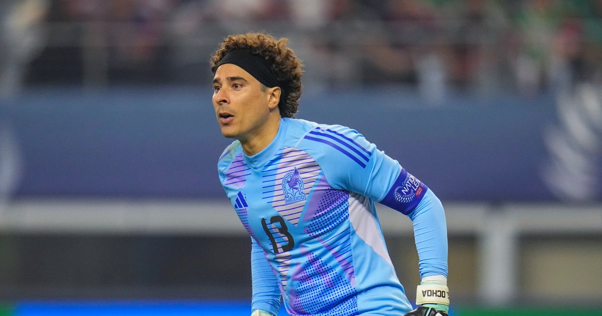 Guillermo Ochoa en acción con AEL Limassol, concentrado en el juego, vistiendo uniforme azul claro y morado.
