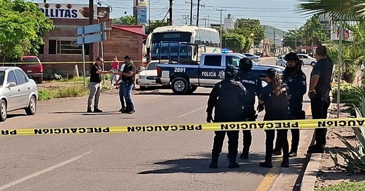 Policías investigan escena del crimen en carretera Guamúchil-Angostura con cinta de precaución y patrulla.