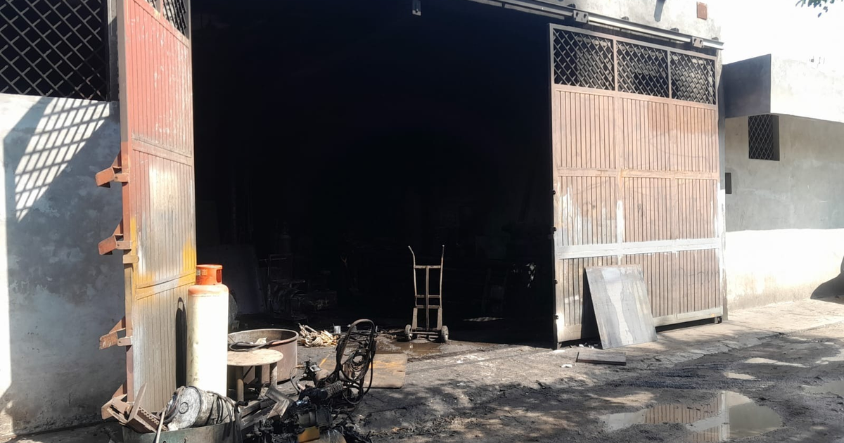 Interior de taller de torno en Mazatlán tras incendio, con puertas metálicas abiertas y objetos en el suelo.