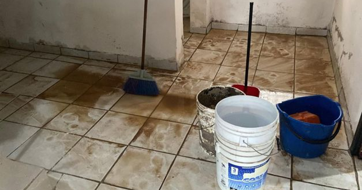 Suelo de baldosas sucio con escoba y baldes tras inundaciones en Mazatlán