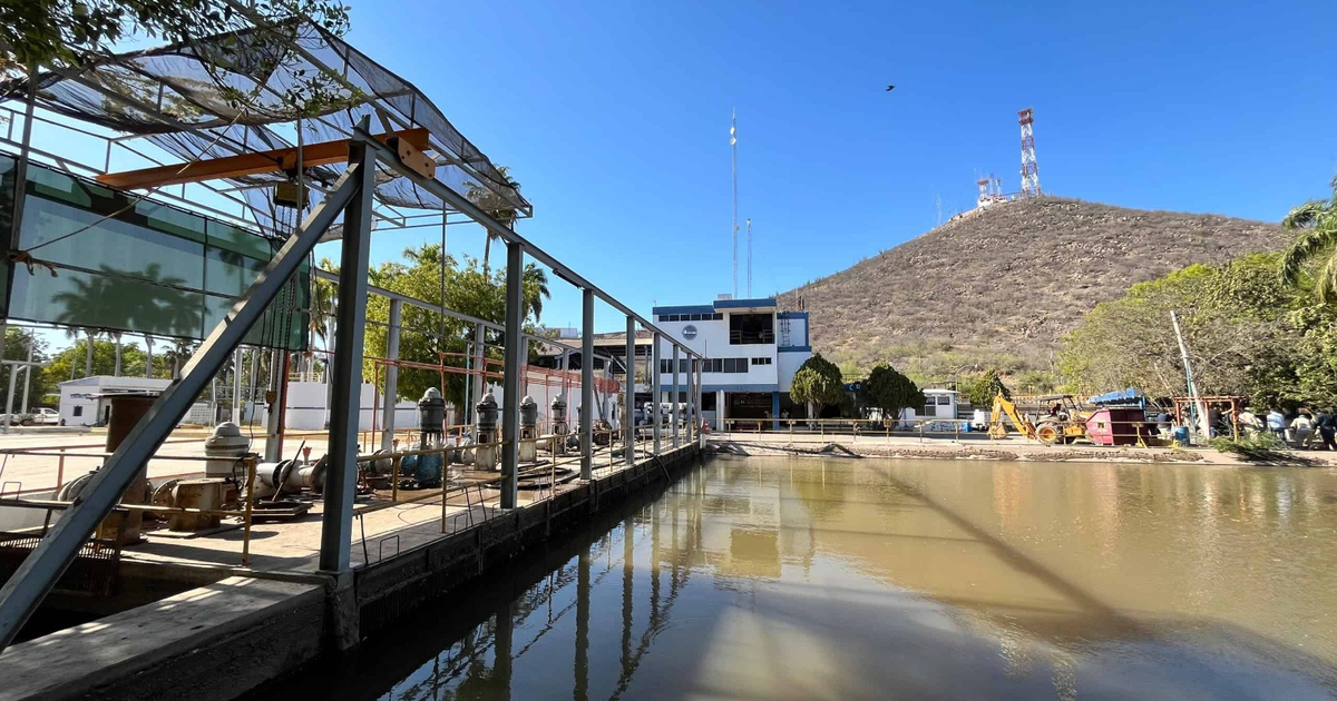 Canal urbano en Los Mochis con estructura metálica y edificio blanco al fondo, afectado por tormenta tropical.