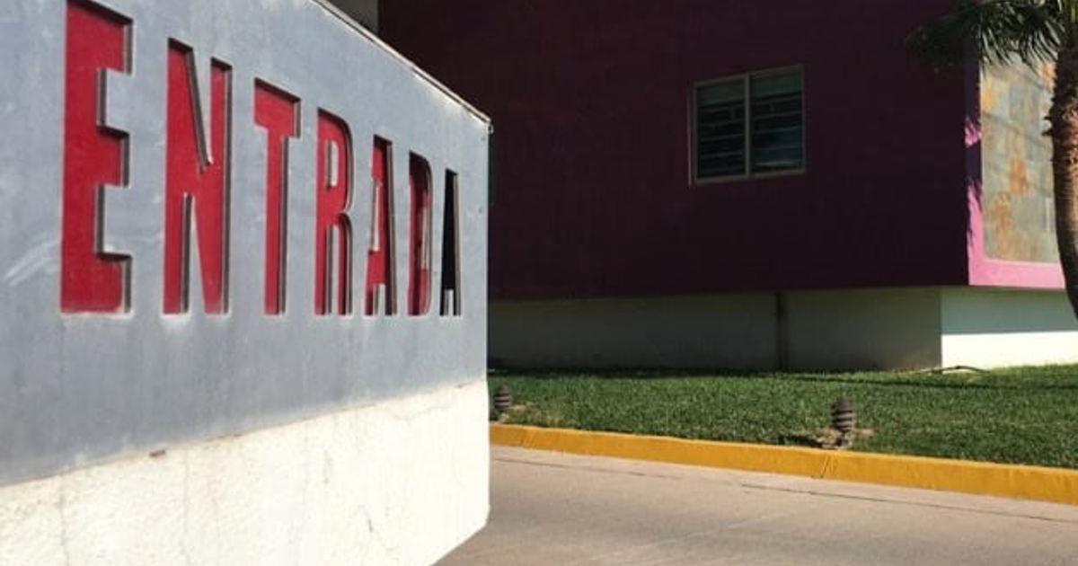 Letrero de 'ENTRADA' en motel de Los Mochis con fondo gris y edificio púrpura