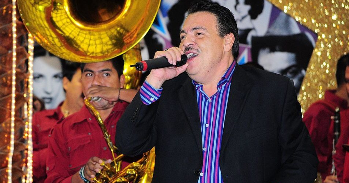 Julio Preciado cantando en un concierto con músicos de fondo
