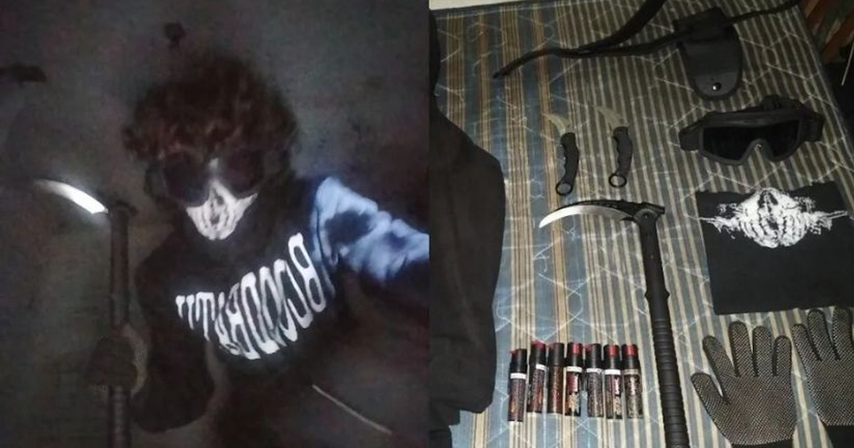 Persona enmascarada con máscara de calavera y guadaña, junto a objetos oscuros en una superficie.