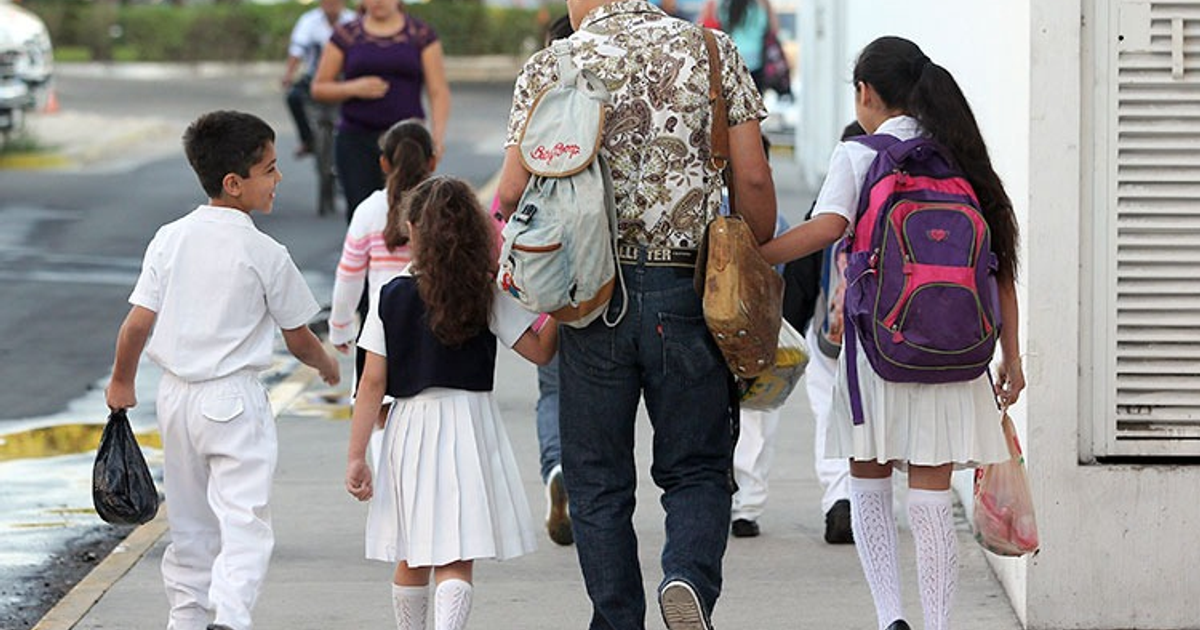 Grupo de niños en uniforme escolar caminando con un adulto en una ciudad