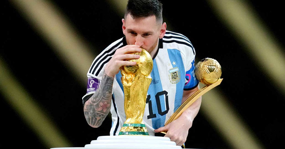 Lionel Messi besando la Copa del Mundo con otro trofeo en mano, celebrando un logro significativo en el fútbol.