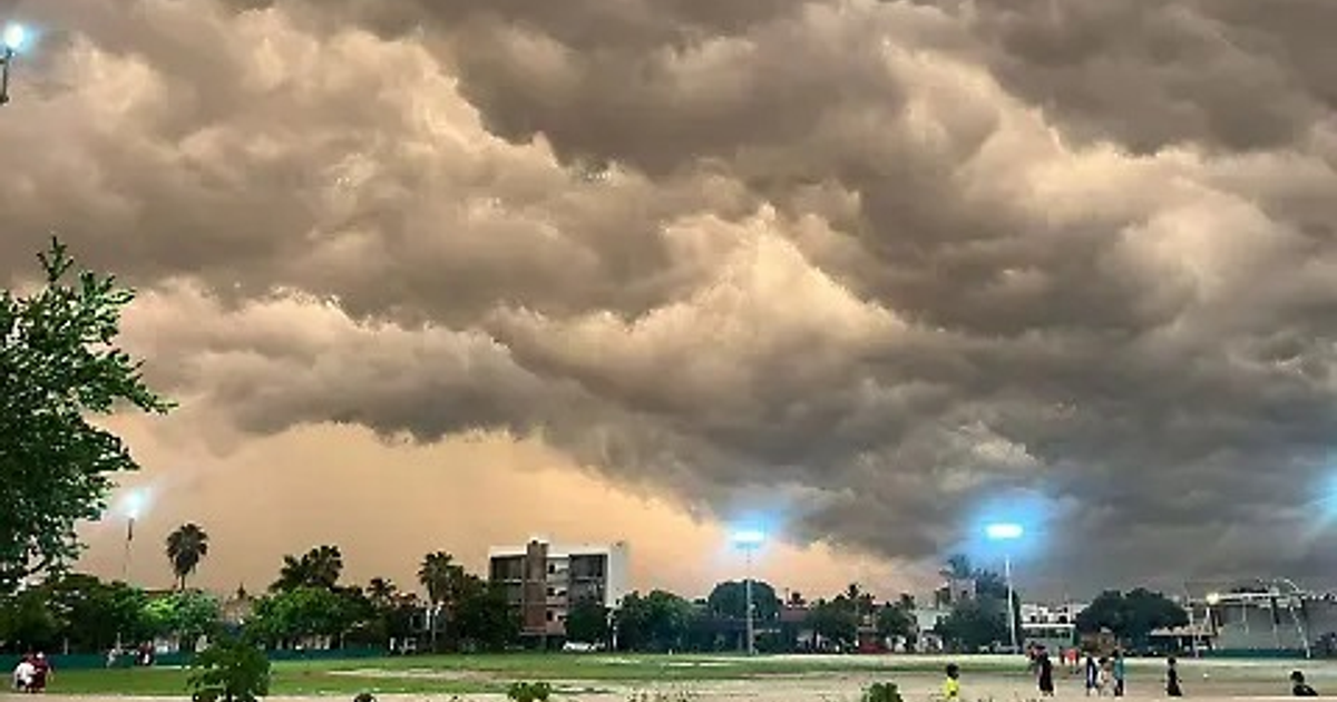 Nubes oscuras sobre un parque en Escuinapa, Sinaloa, con luces encendidas y personas presentes, anticipando una tormenta.