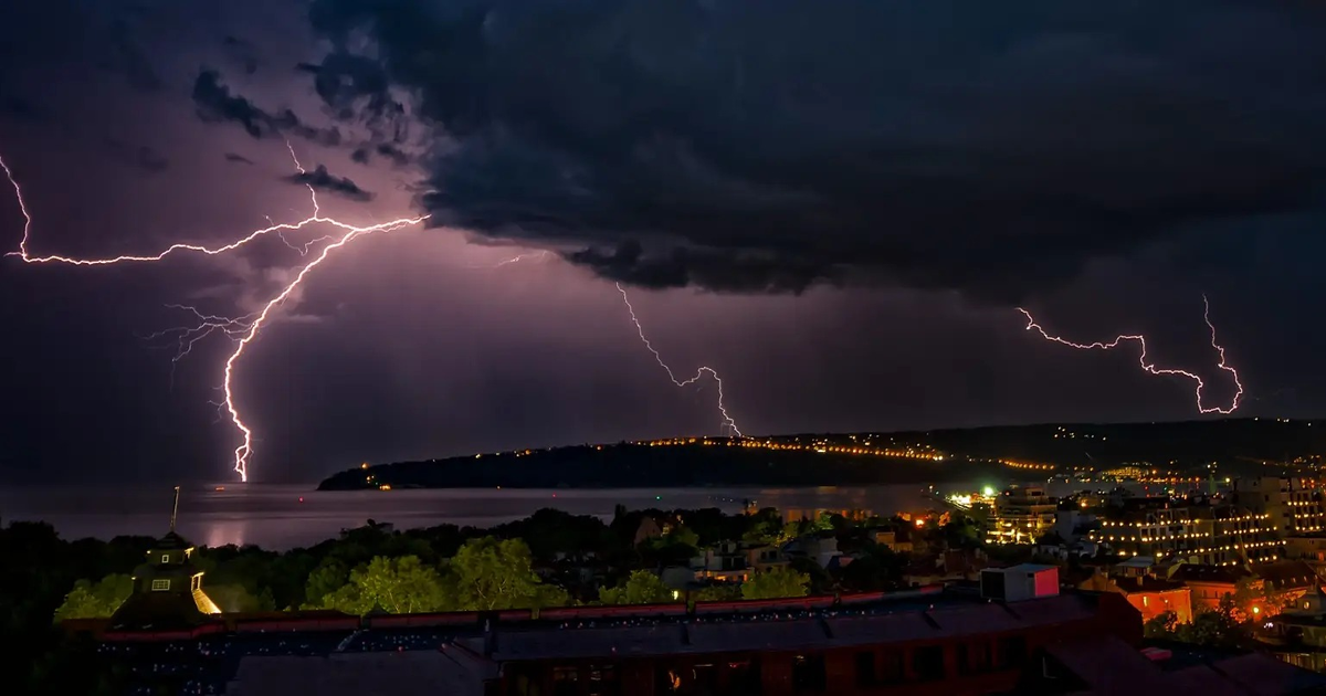 Paisaje nocturno con relámpagos sobre un lago y edificios en Sinaloa durante un temporal.
