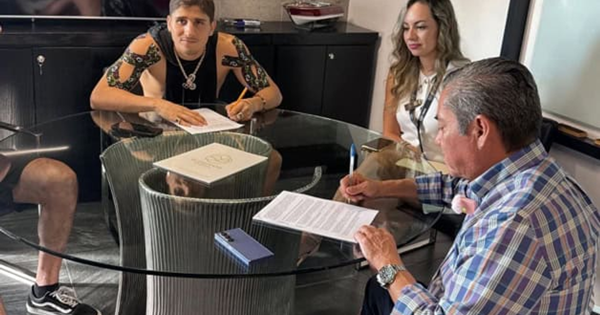 Personas en una reunión de oficina revisando documentos y firmando acuerdos.
