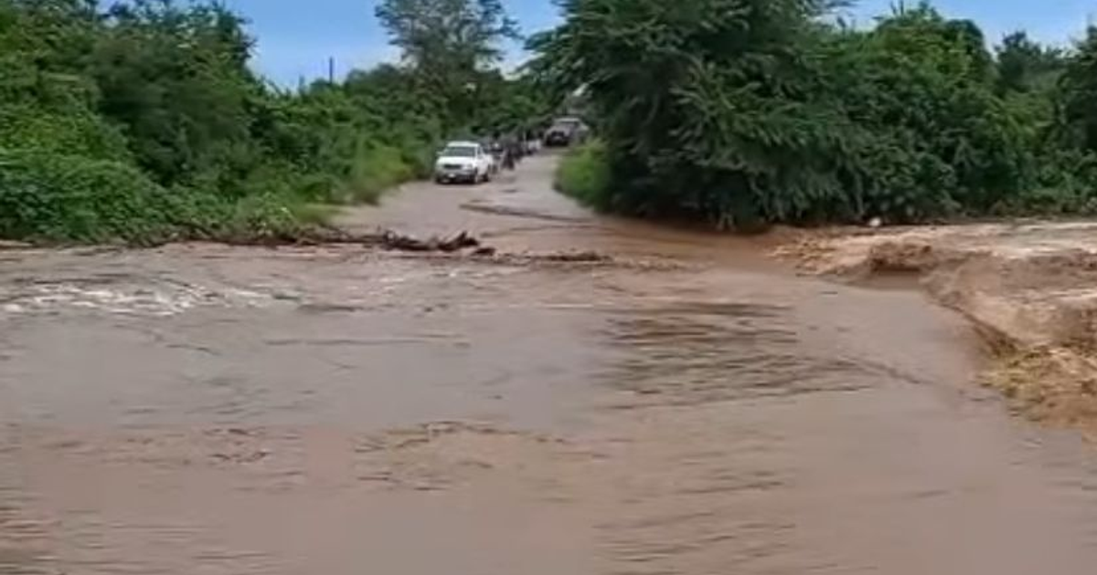 Camino inundado en El Recodo, Mazatlán, con agua estancada y vehículos estacionados.