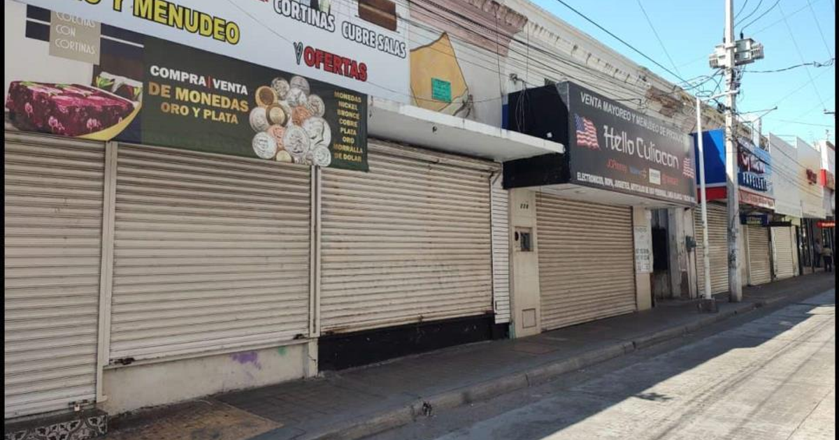 Calle de Culiacán con locales cerrados y letreros de servicios, reflejando el impacto económico en Sinaloa.